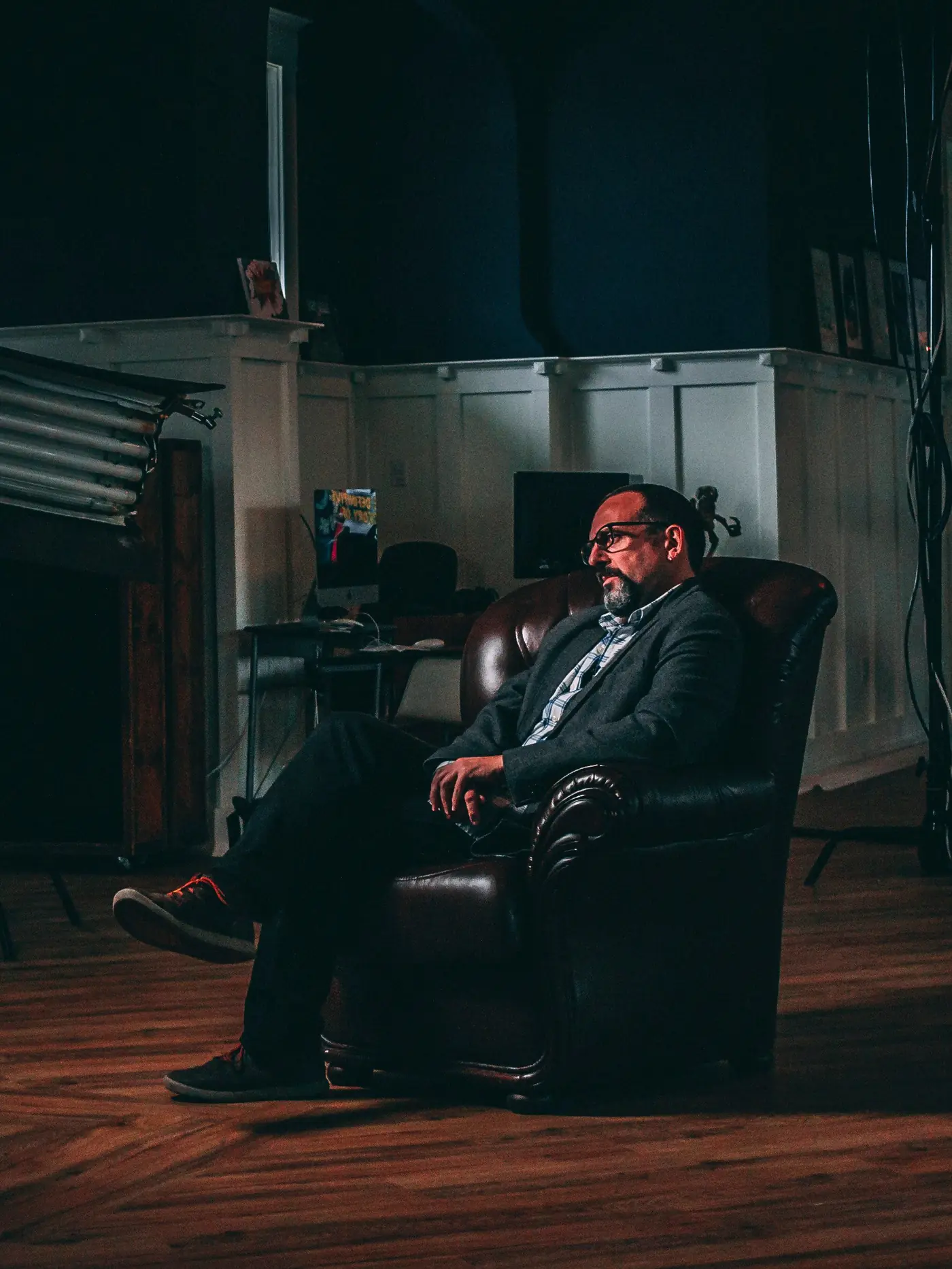 Man sitting in a leather armchair in a dark study